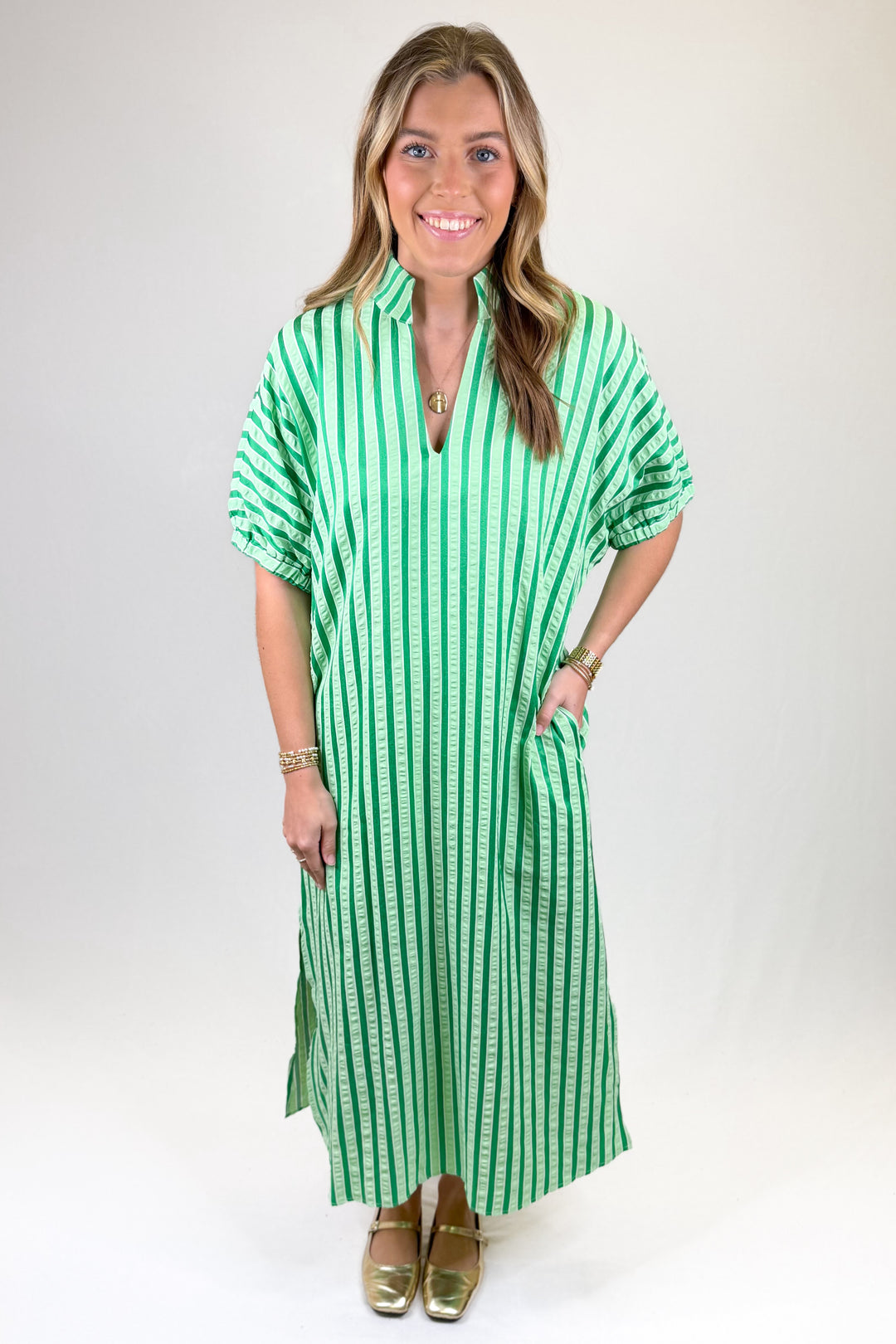 Woman wearing a green and white striped dress against a plain background