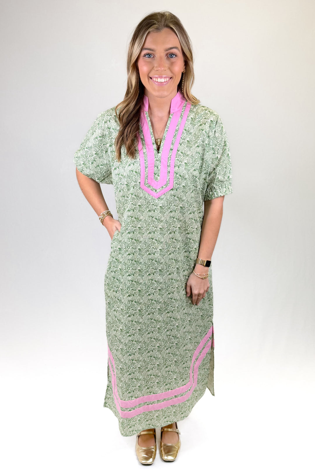 Woman wearing a green dress with pink accents on a white background