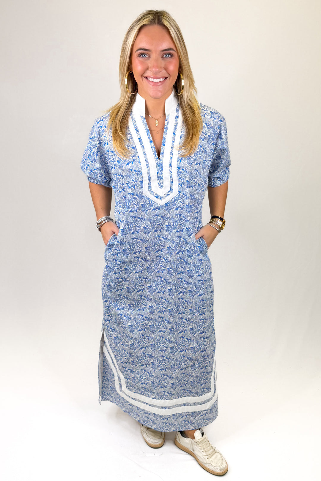 Woman wearing a blue patterned dress with white trim on a plain background