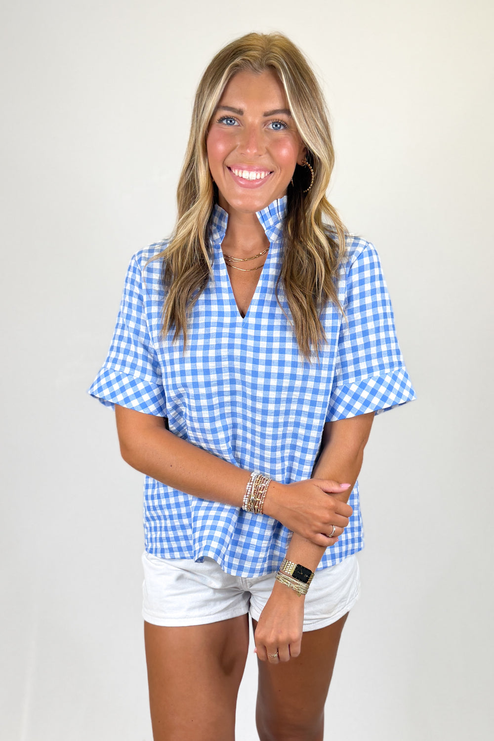 Woman wearing a blue and white checkered shirt with a plain background