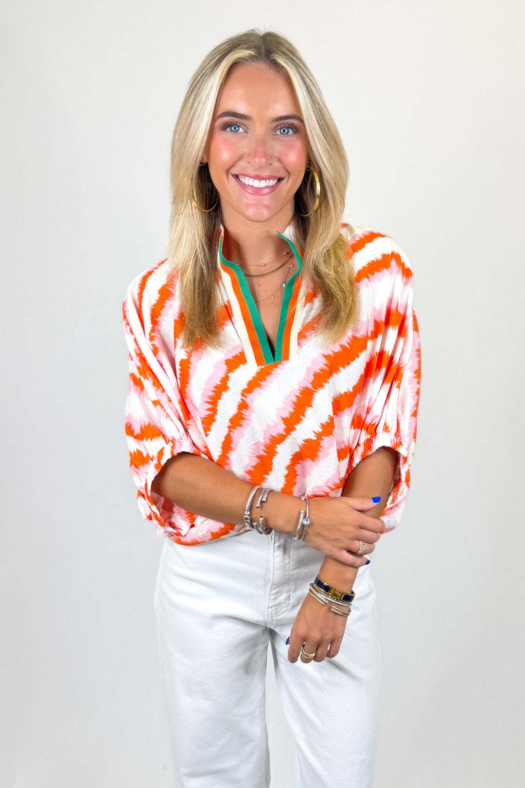 Woman wearing a tie-dye shirt with orange and white stripes on a plain background