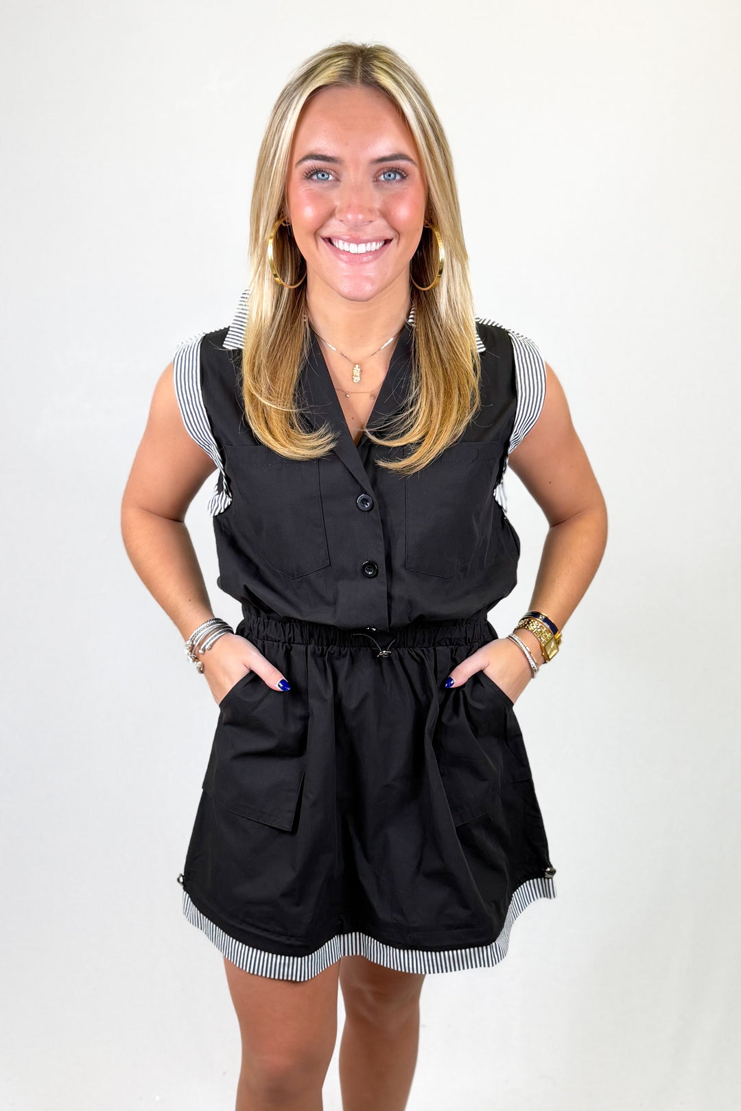 Woman wearing a black romper with white trim on a white background