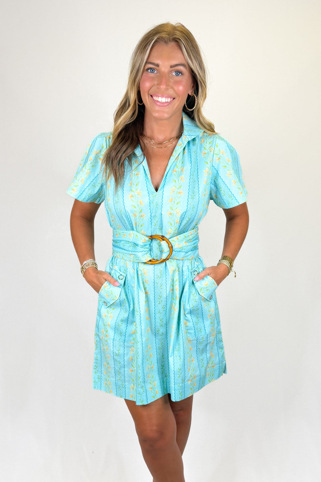 Woman wearing a light blue dress with a belt on a white background