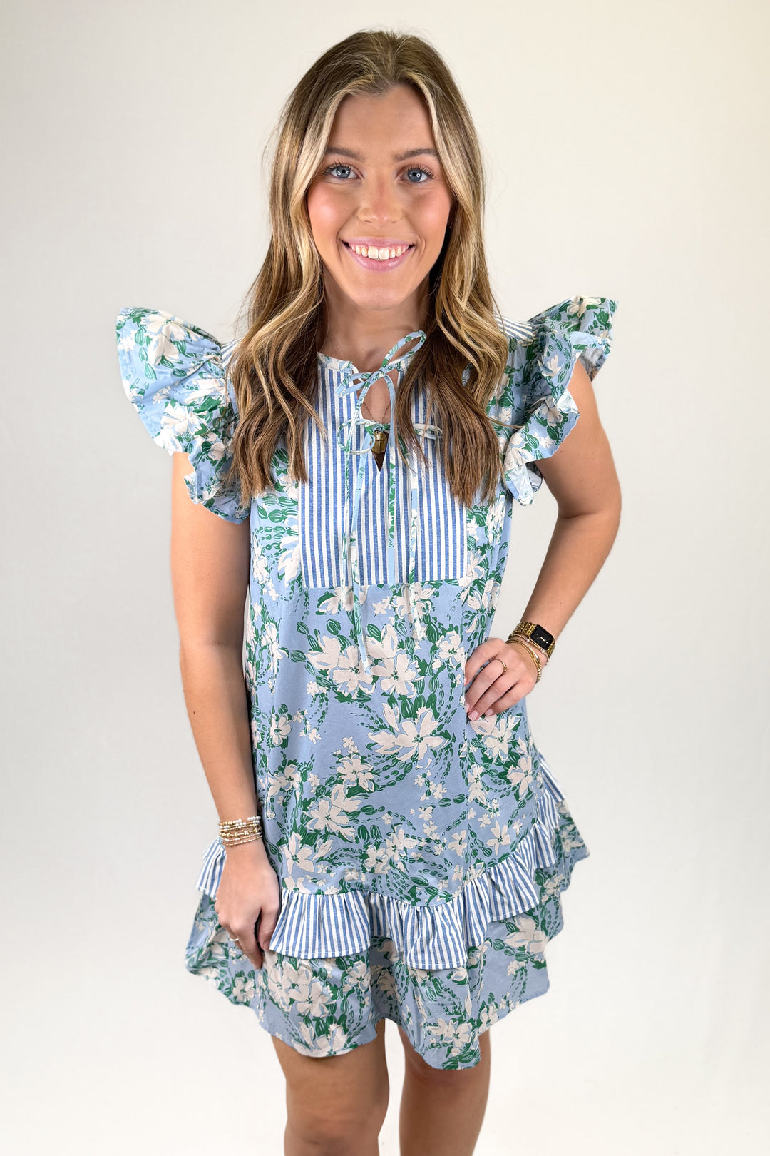 Woman wearing a floral dress with ruffled sleeves and hem on a plain background
