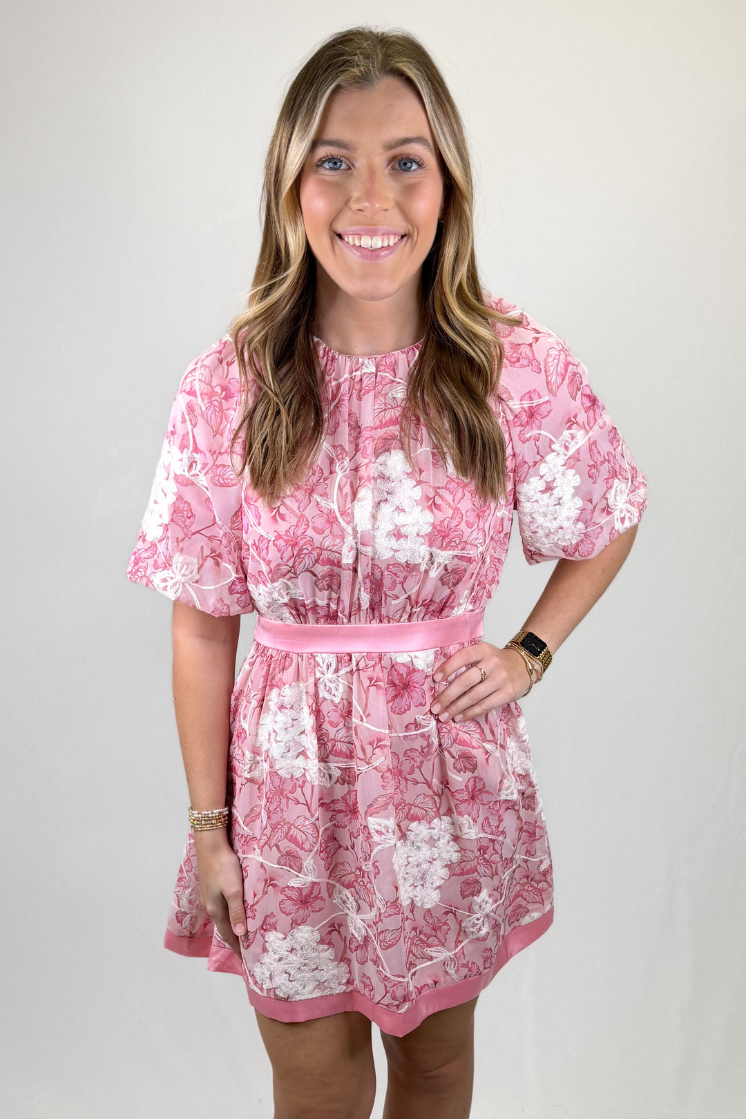 Woman wearing a pink floral dress against a plain background
