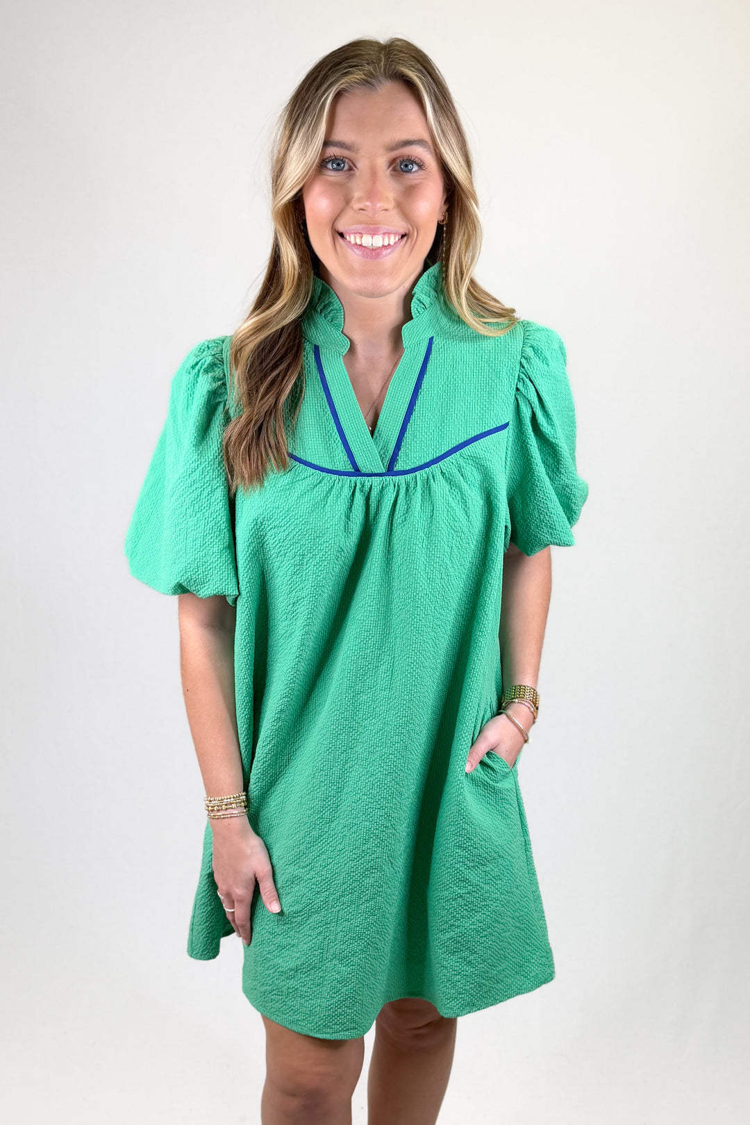 Woman wearing a green dress with puff sleeves against a white background