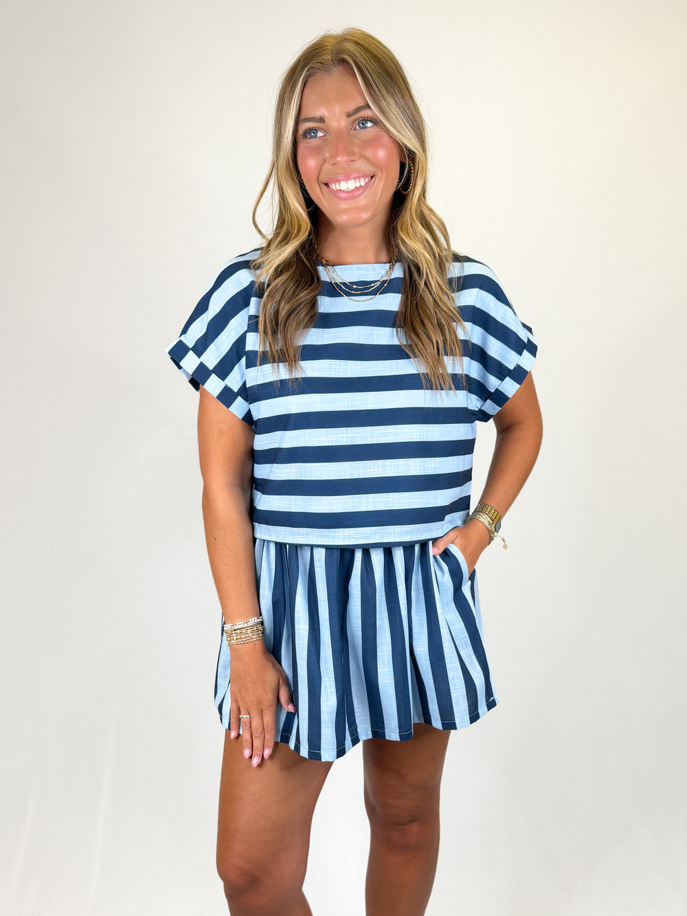 Woman wearing a blue and navy striped skirt set on a plain background