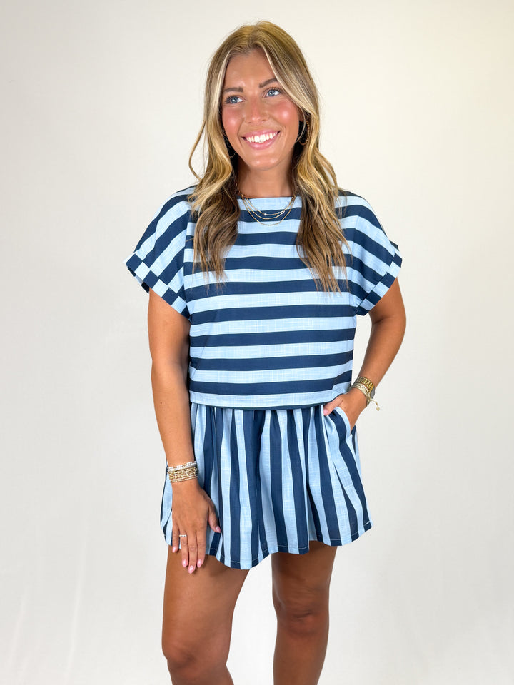 Woman wearing a blue and navy striped skirt set on a plain background