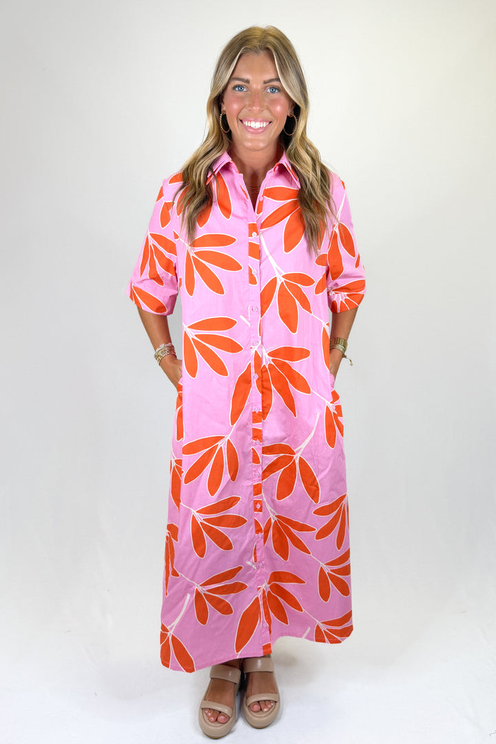 Woman wearing a pink dress with orange leaf patterns on a white background