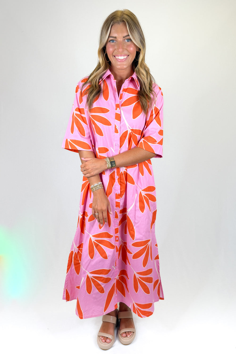 Woman wearing a pink dress with orange floral pattern on a white background