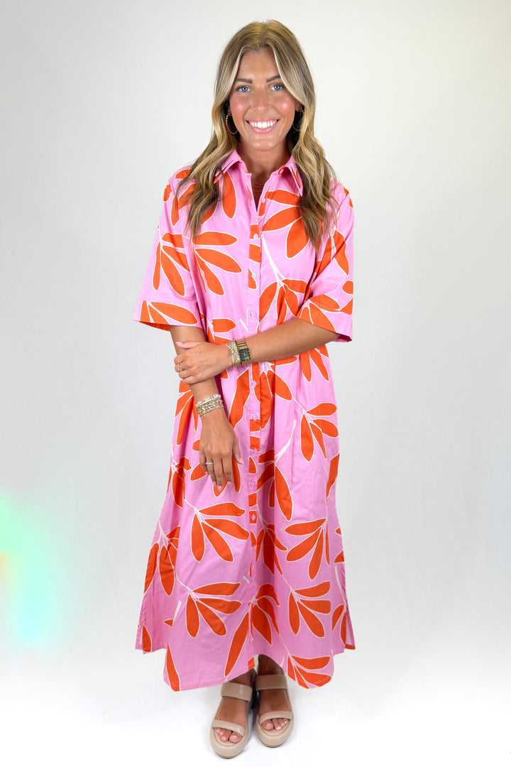 Woman wearing a pink dress with orange floral pattern on a white background