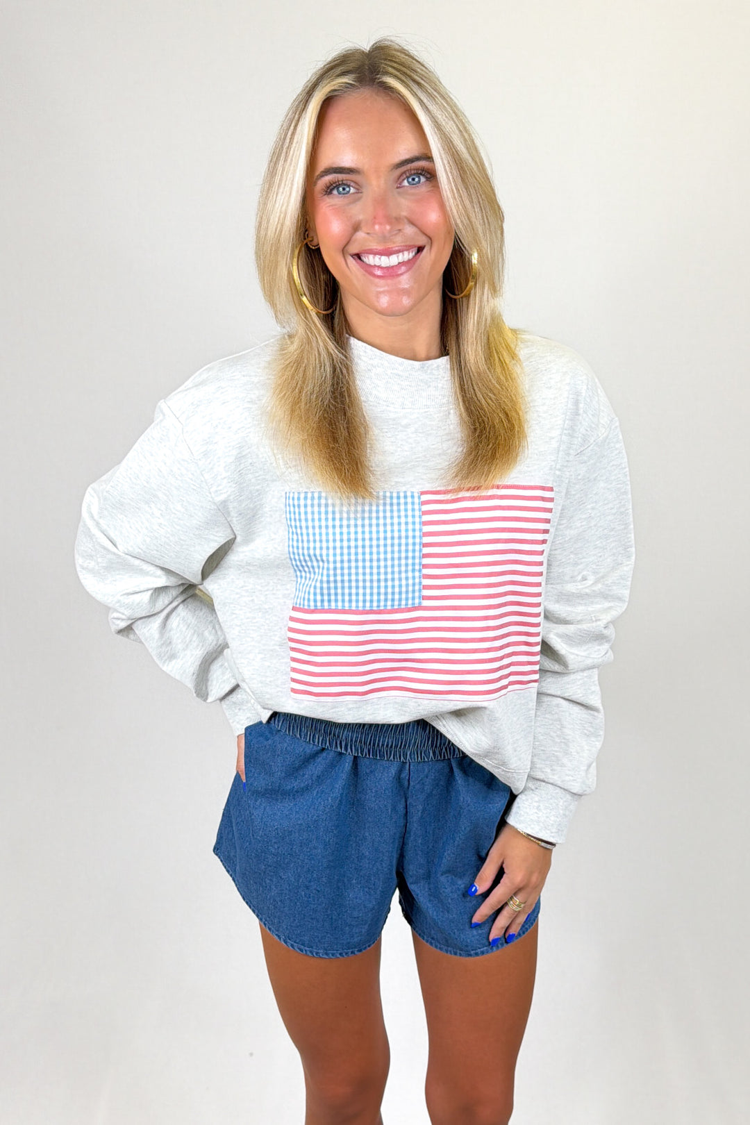 Woman wearing a sweatshirt with an American flag design on a plain background