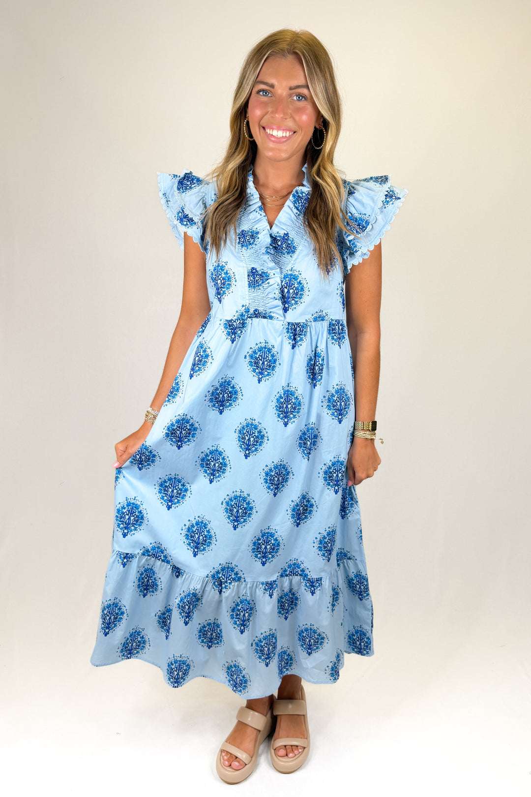 Woman wearing a blue floral dress against a plain background