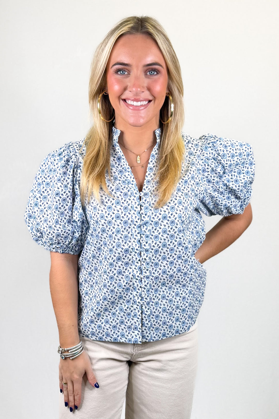 Woman wearing a blue floral blouse with puffed sleeves against a white background