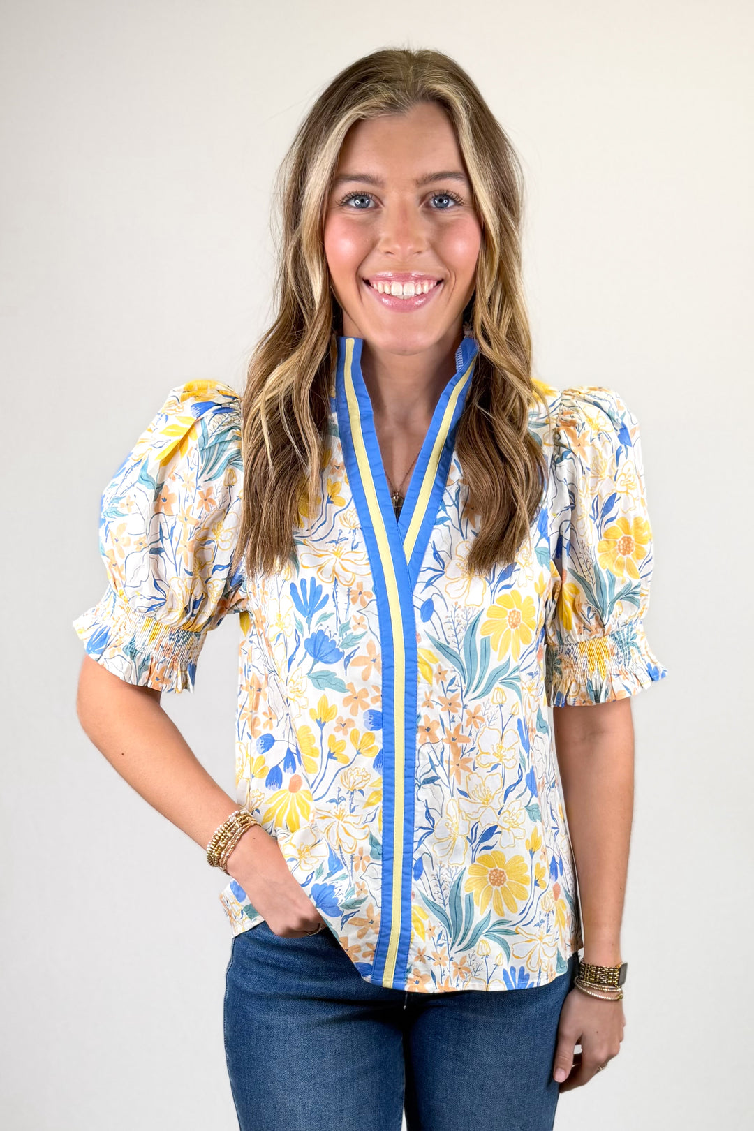 Woman wearing a floral blouse with blue accents on a plain background
