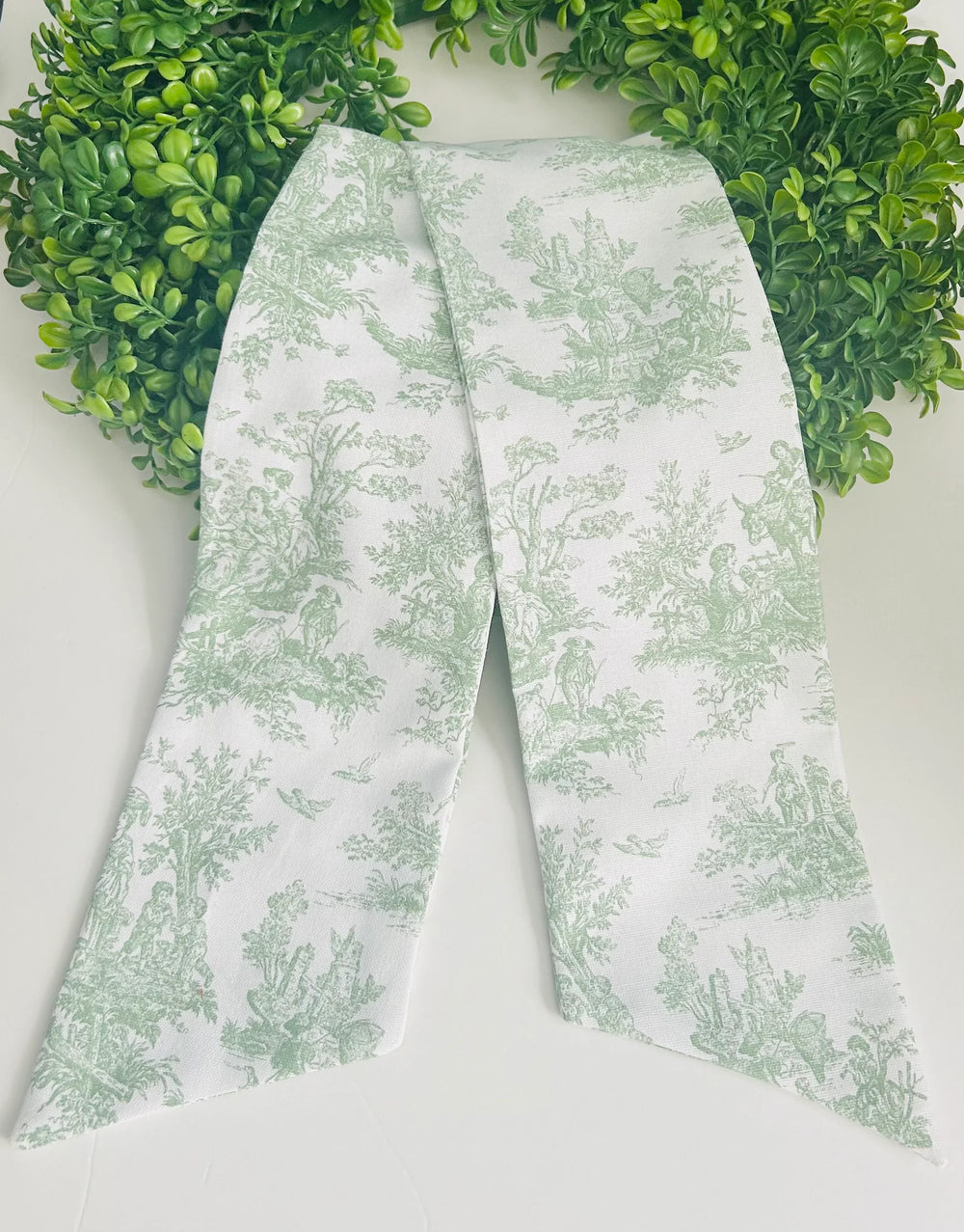 Green floral-patterned fabric on a white background with a green wreath in the corner.