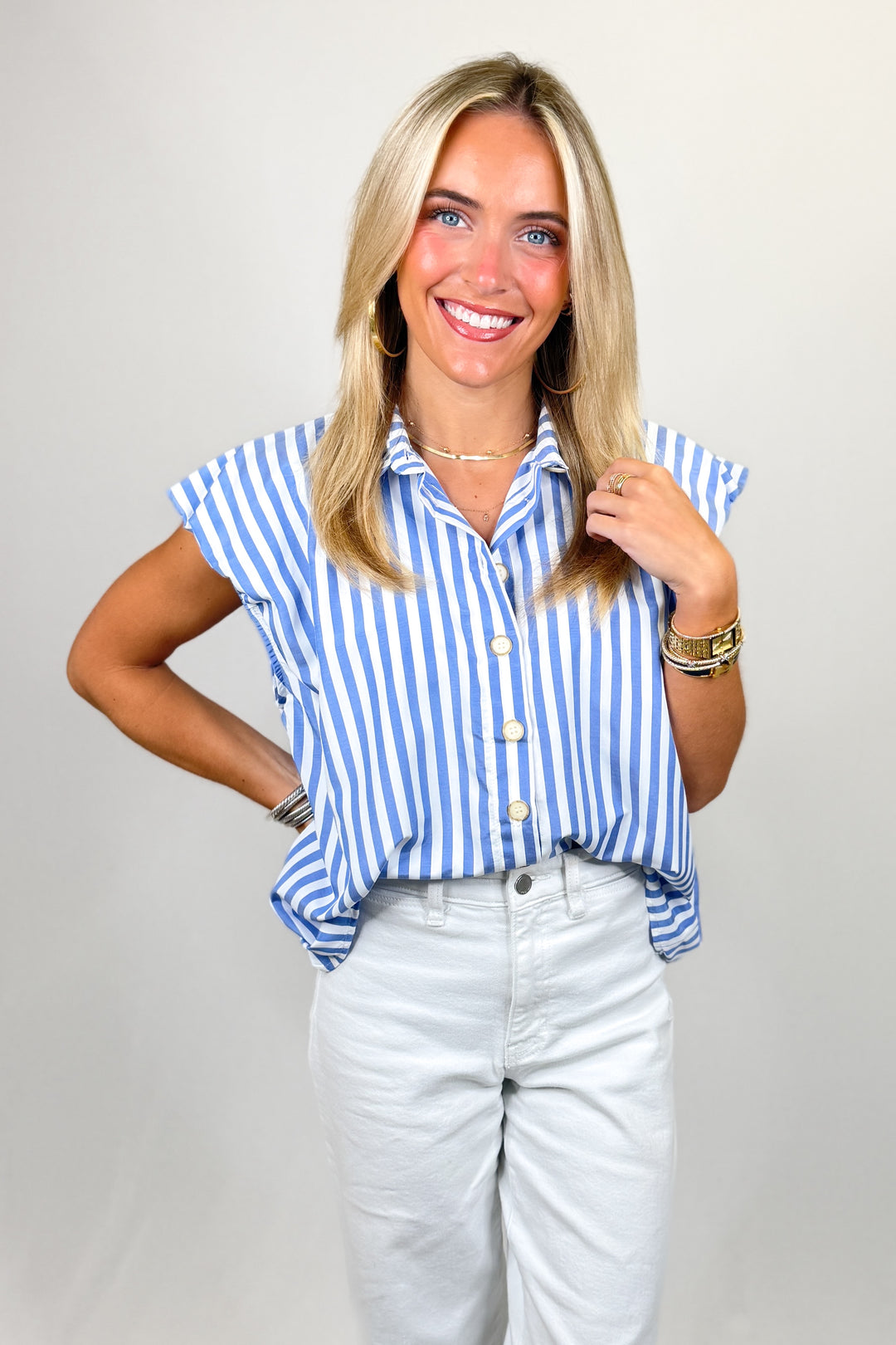 Woman wearing a blue and white striped shirt with ruffled sleeves against a plain background