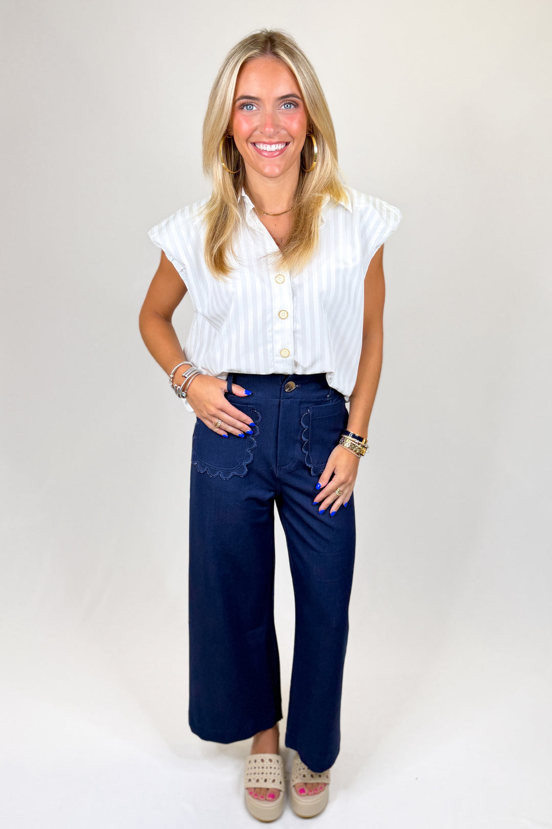 Woman wearing a white blouse and blue pants on a plain background