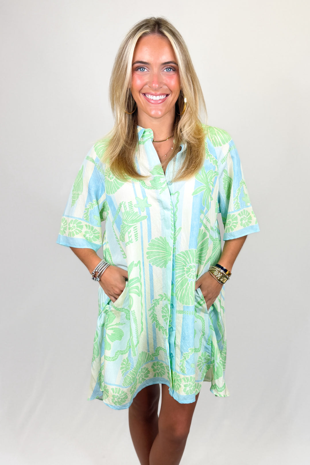 Woman wearing a green and white patterned dress on a gray background