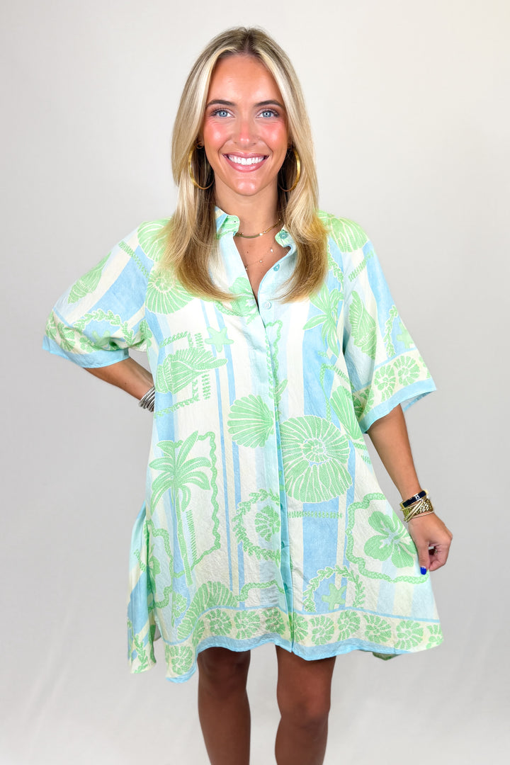 Woman wearing a light blue and green patterned dress on a plain background