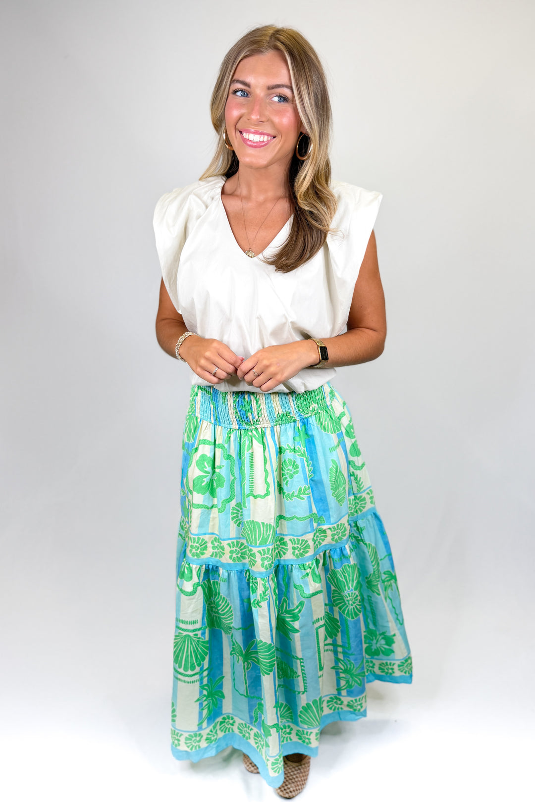 Woman wearing a white top and a colorful skirt with a white background