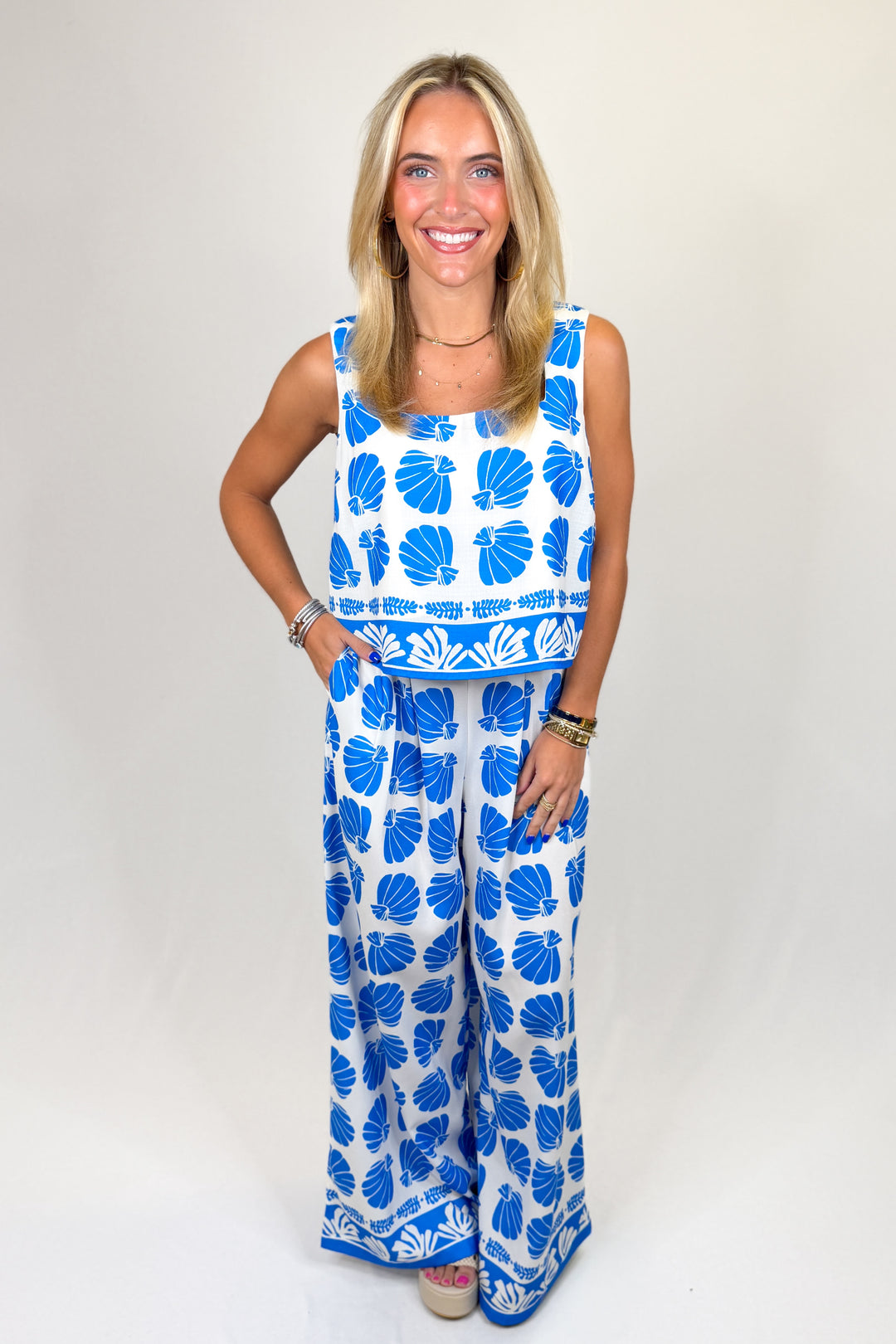 Woman wearing a blue and white floral outfit on a plain background