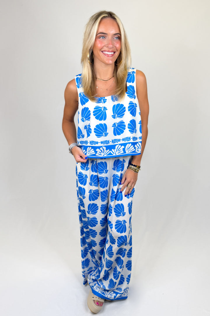 Woman wearing a blue and white floral dress on a plain background
