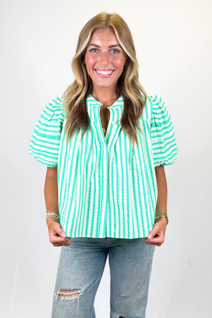 woman wearing a green seersucker top against a white background