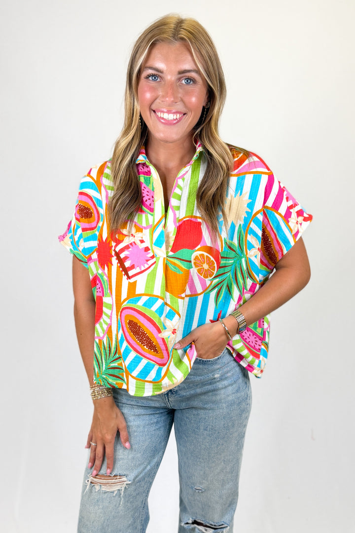 Woman wearing a colorful patterned shirt with a plain background