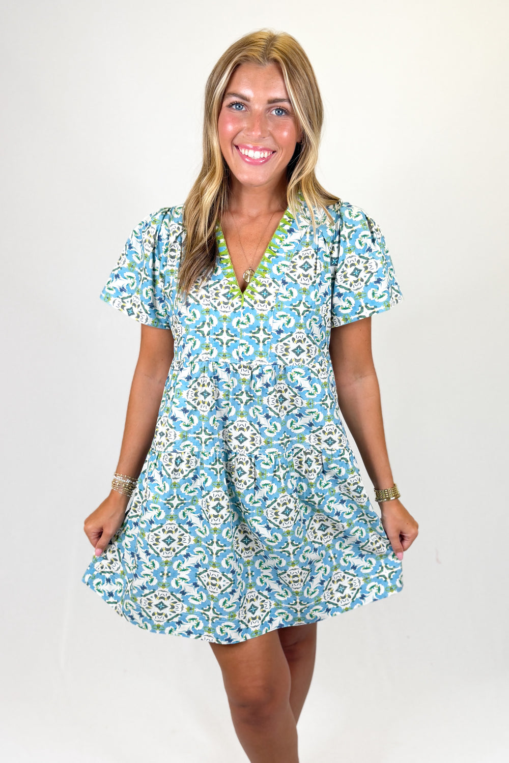 Woman wearing a blue geometric pattern mini dress against a white background