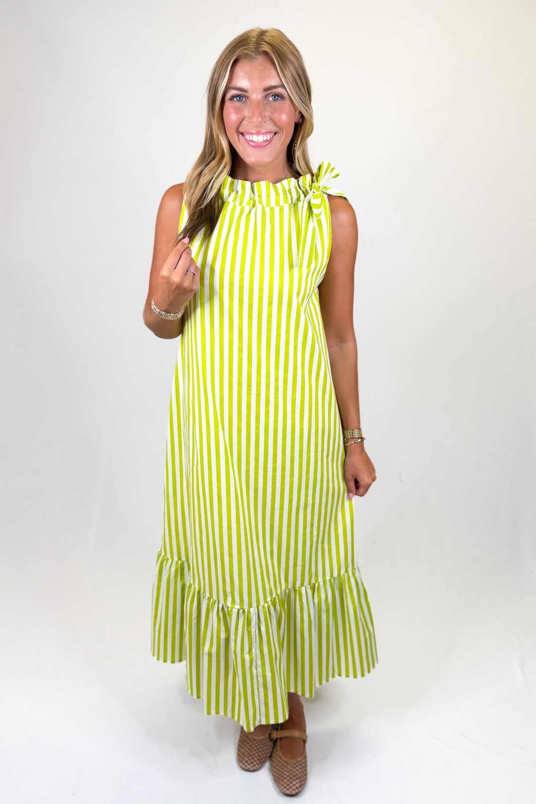 woman wearing a lime green and white striped midi dress against a white background