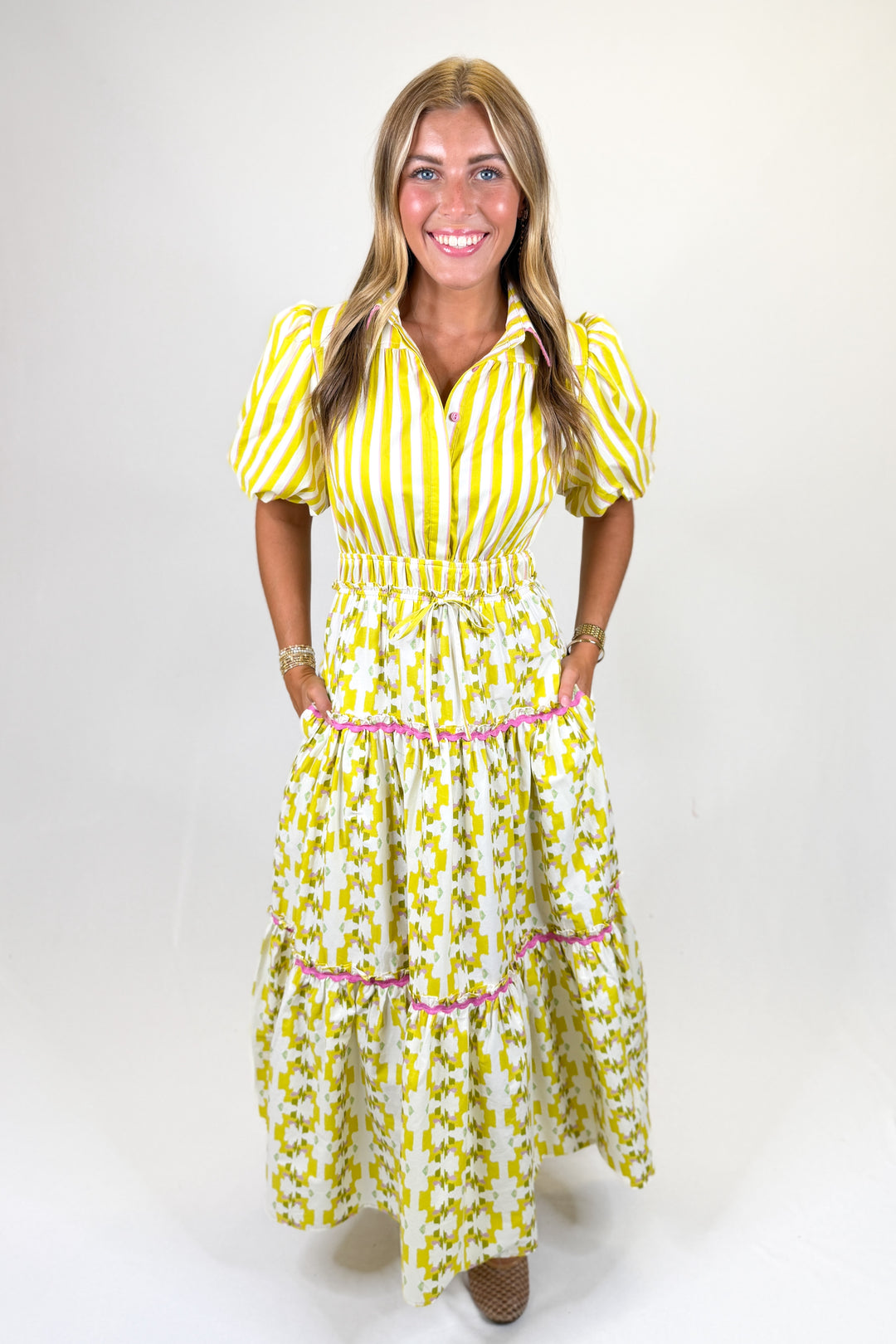 Woman wearing a yellow and white striped dress with a belt on a white background