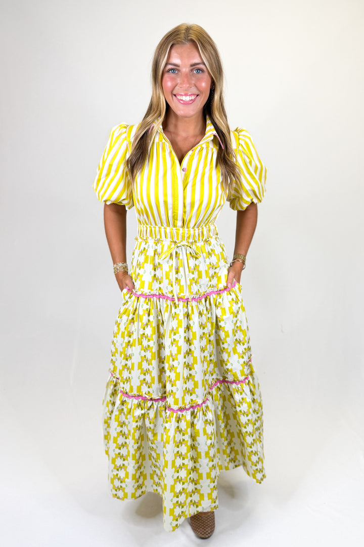 Woman wearing a yellow and white striped dress with a belt on a white background