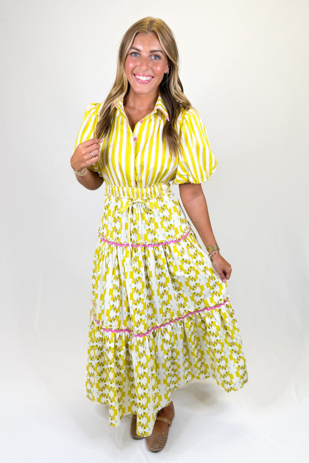 Woman wearing a yellow and white striped dress with a belt on a white background