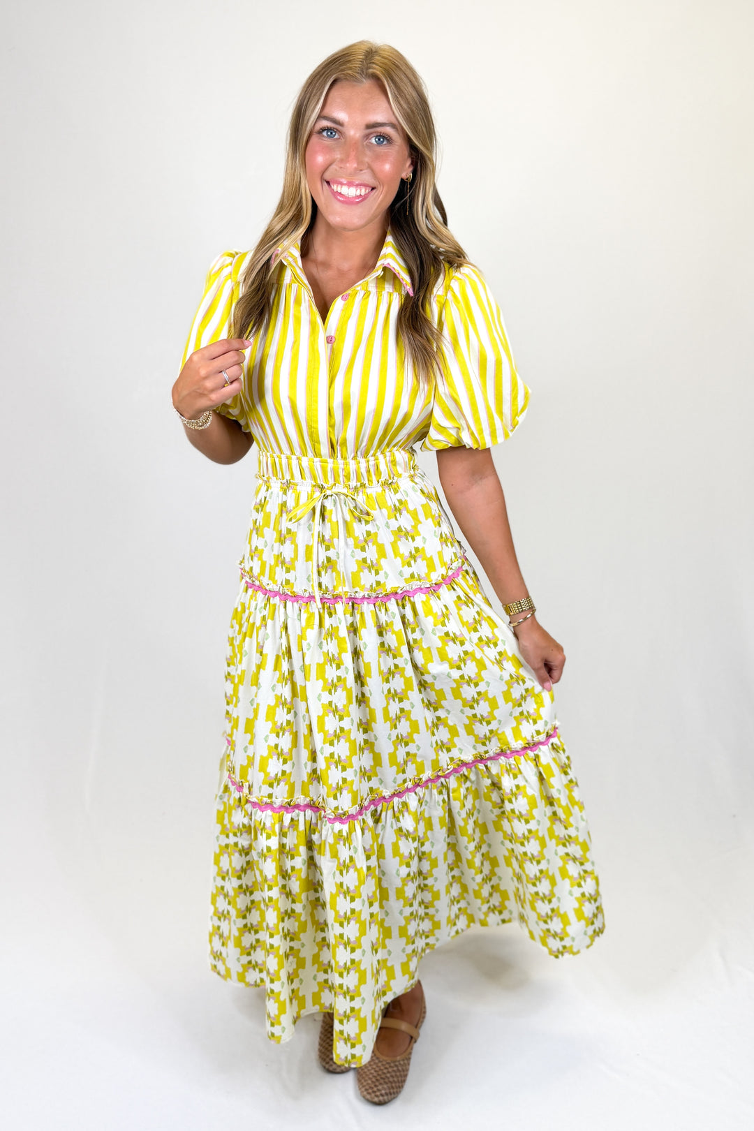 Woman wearing a yellow and white striped dress with a belt on a white background