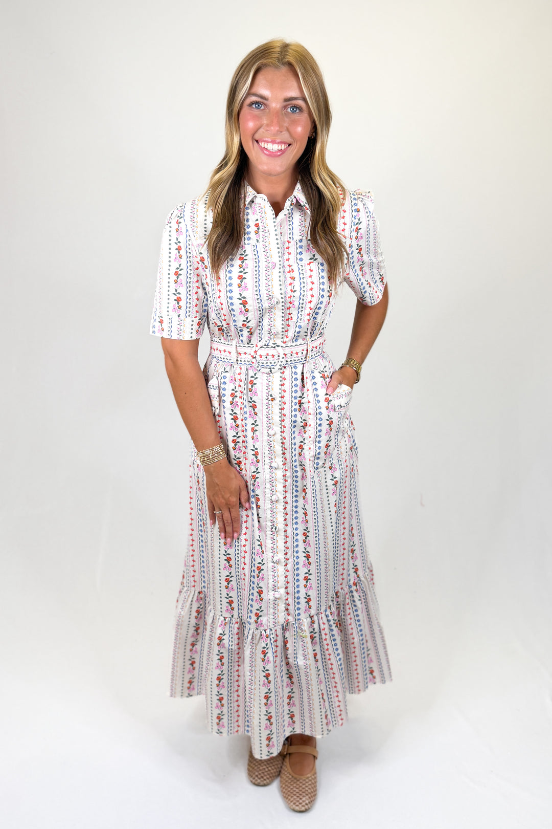 woman wearing a belted floral printed dress against a white background