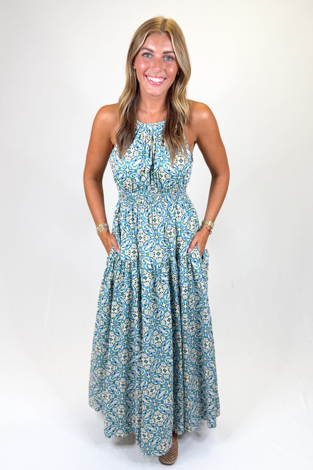 Woman wearing a blue pattern halter maxi dress against a white background