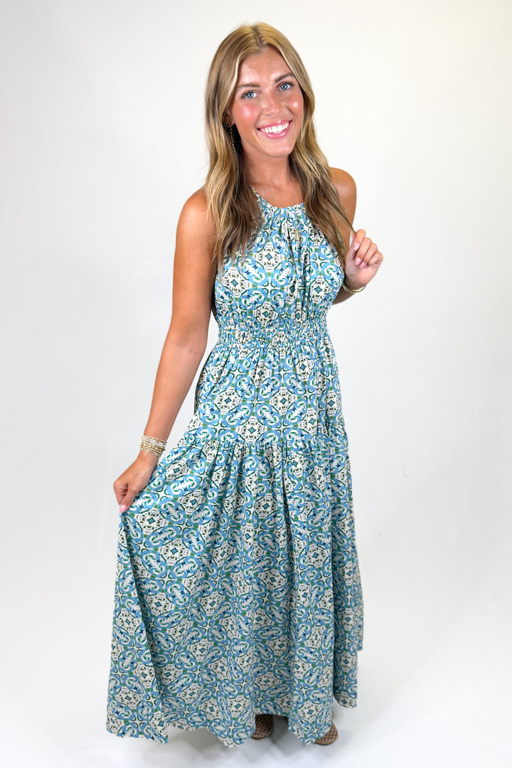Woman wearing a blue pattern halter maxi dress against a white background