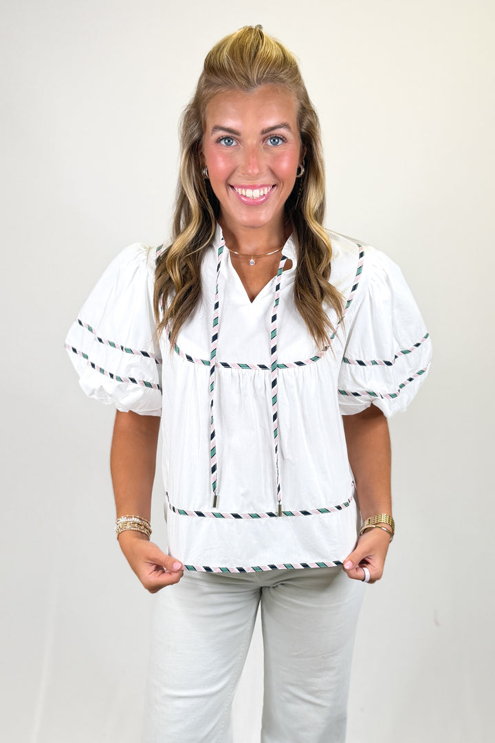 woman wearing a white puff sleeve top against a white background