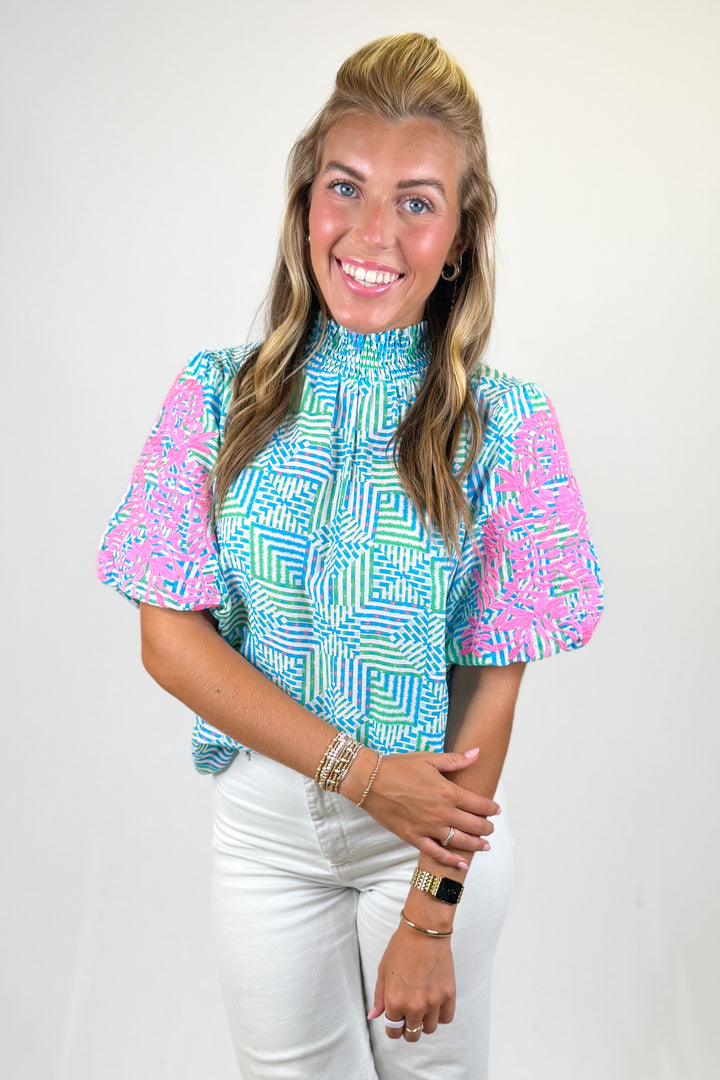 Woman wearing a colorful patterned shirt with a plain background