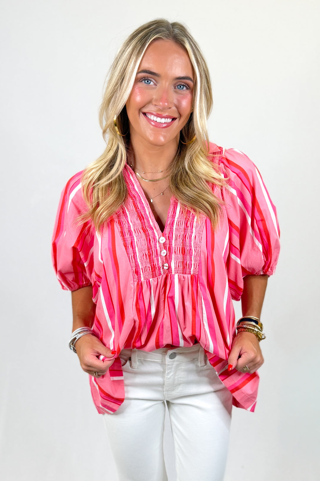 woman wearing a pink striped top with buttons against a white background