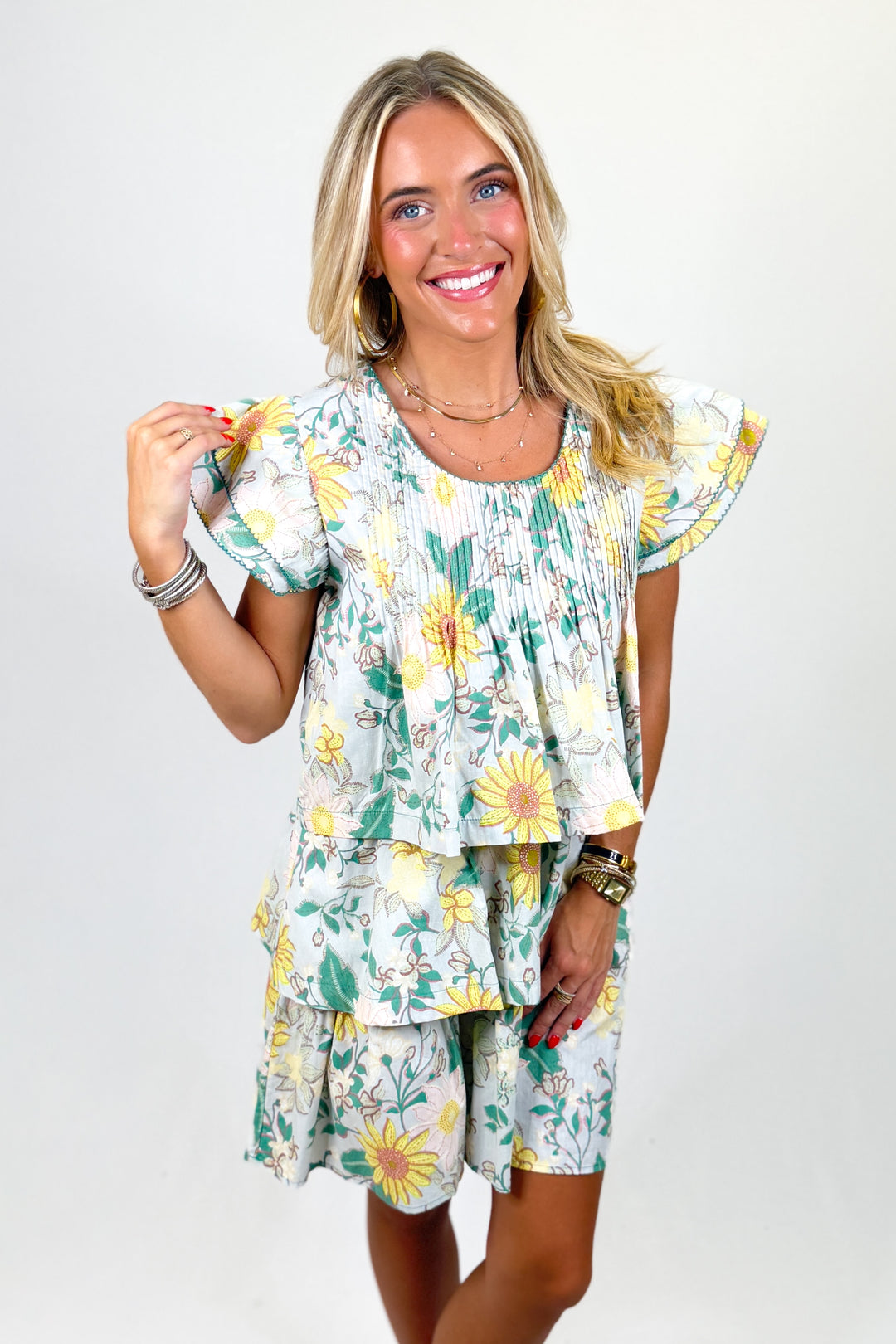 Woman wearing a floral dress with yellow flowers on a plain background