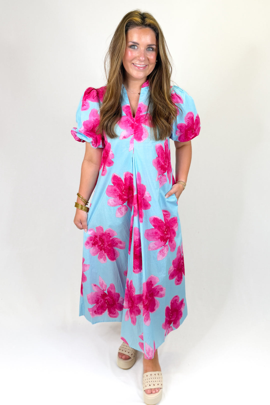 Woman wearing a light blue dress with pink floral pattern on a white background