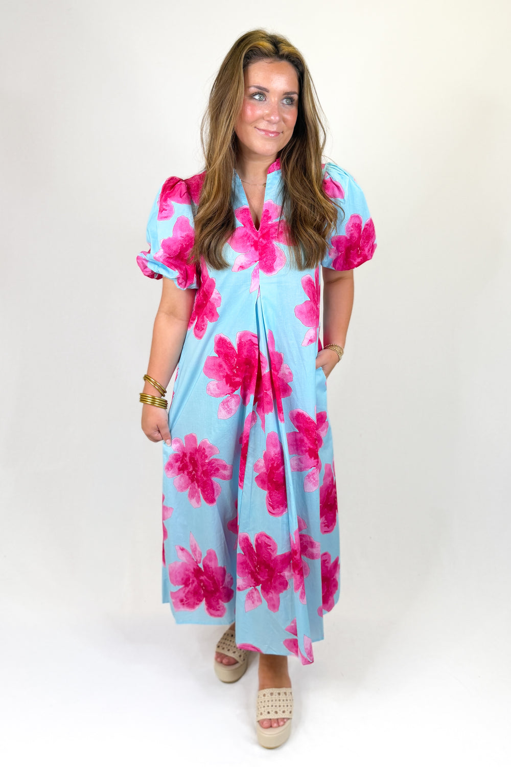 Woman wearing a light blue dress with pink floral patterns on a white background