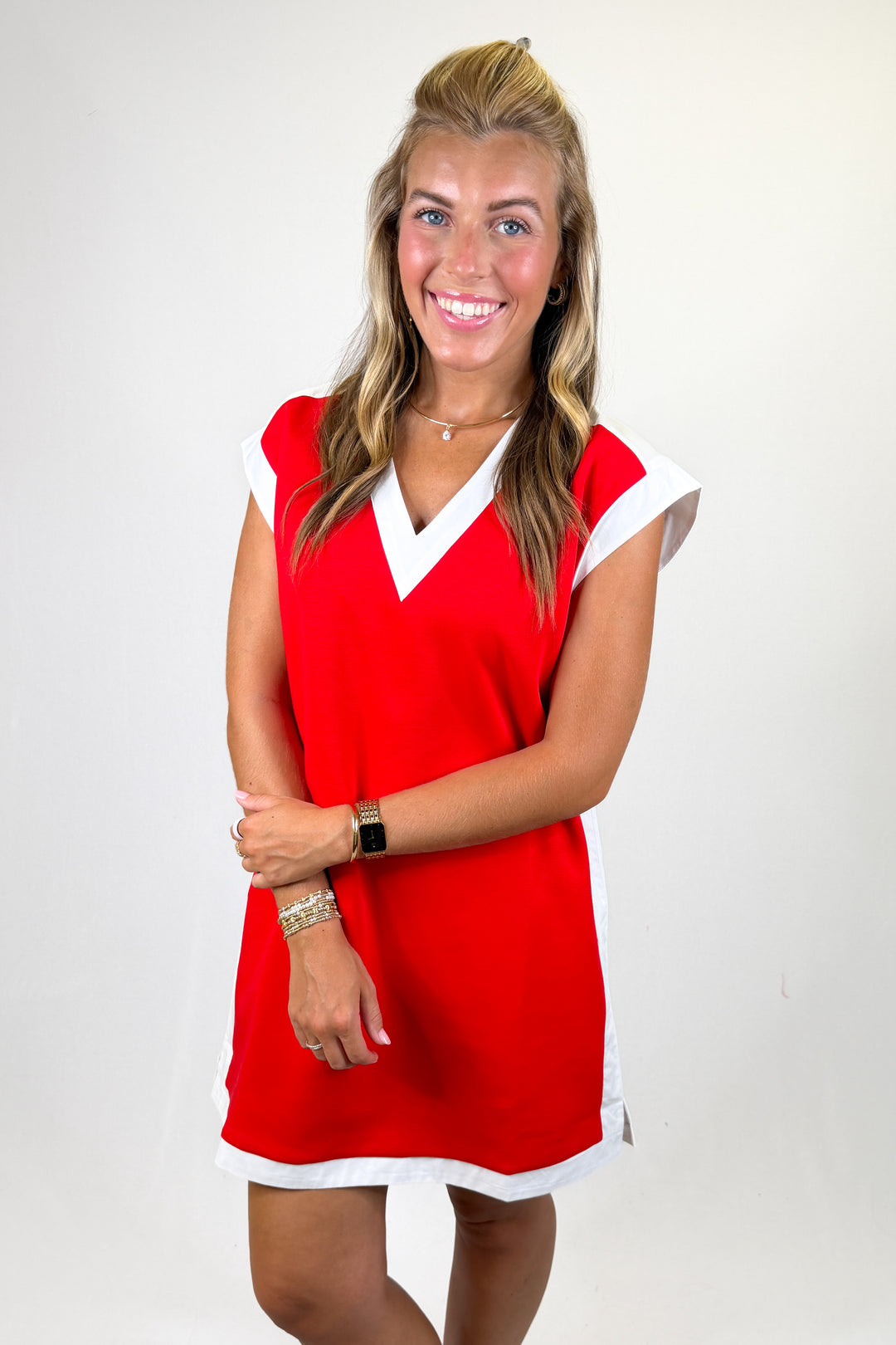 Woman wearing a red dress with white trim on a plain background
