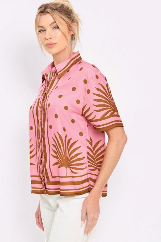 Woman wearing a pink shirt with brown palm tree pattern on a white background