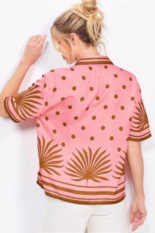 Woman wearing a pink shirt with brown patterns on a white background