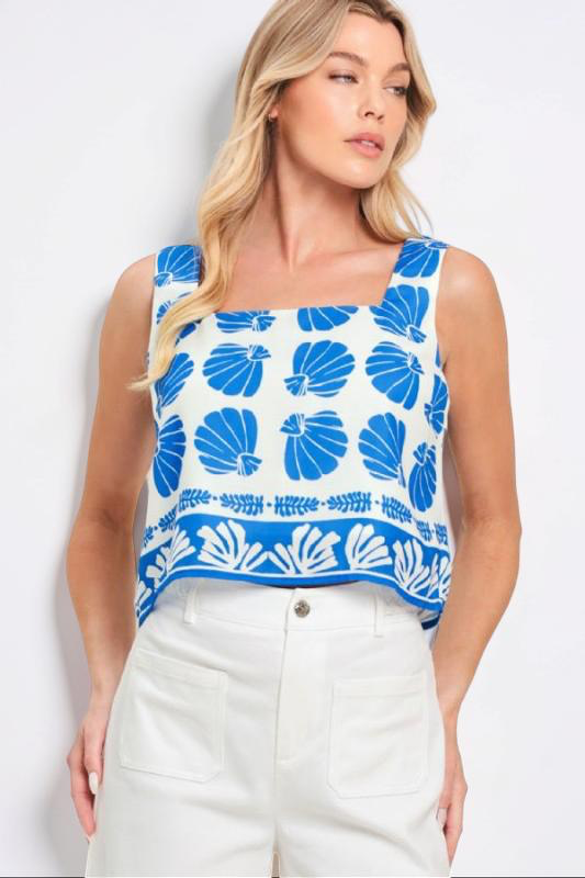 Woman wearing a sleeveless top with blue shell pattern on a white background