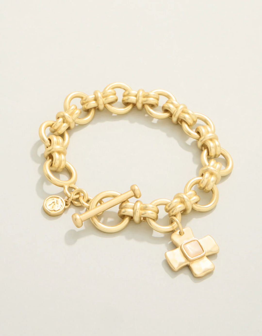 Gold chain bracelet with charms on a light beige background