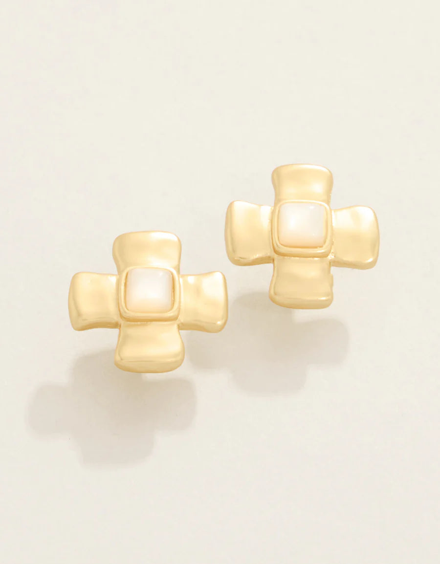 Pair of gold cross-shaped earrings on a light beige background